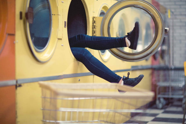 A person's legs sticking out of a large washing machine