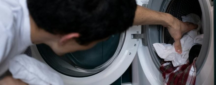 man putting clothes in washing machine