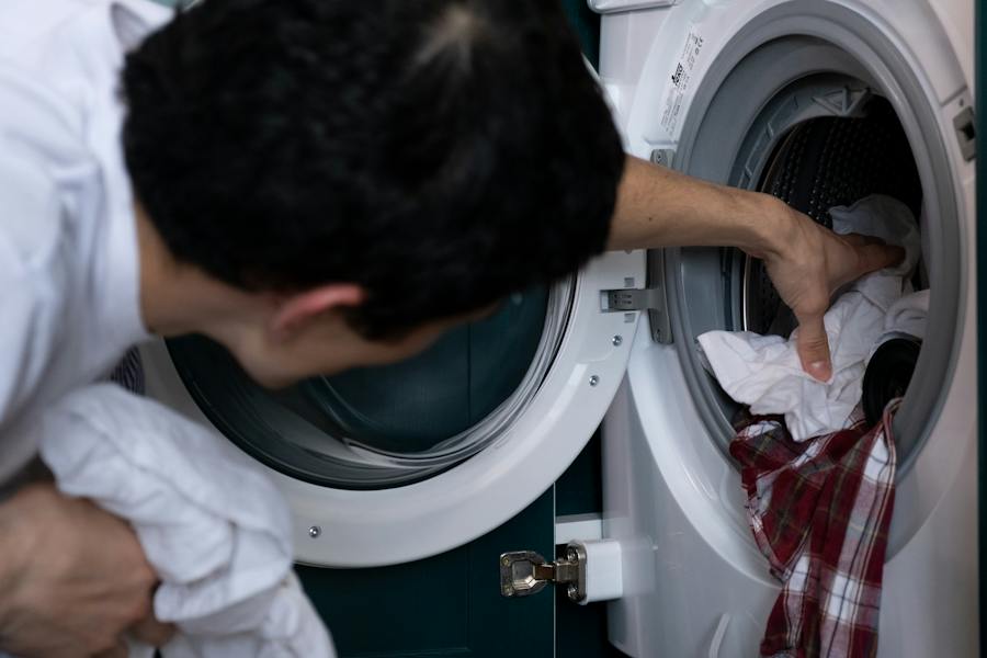 man putting clothes in washing machine