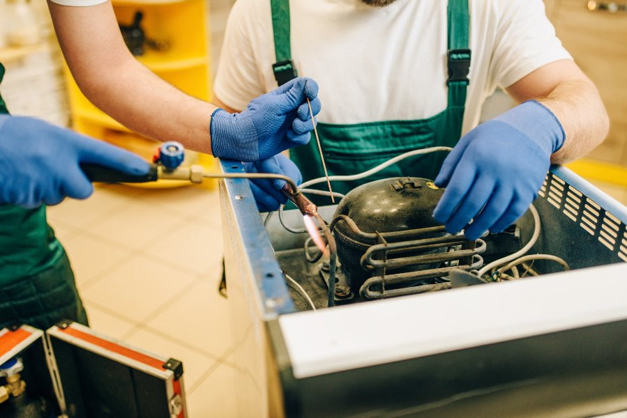 technicians repair refrigerator at home